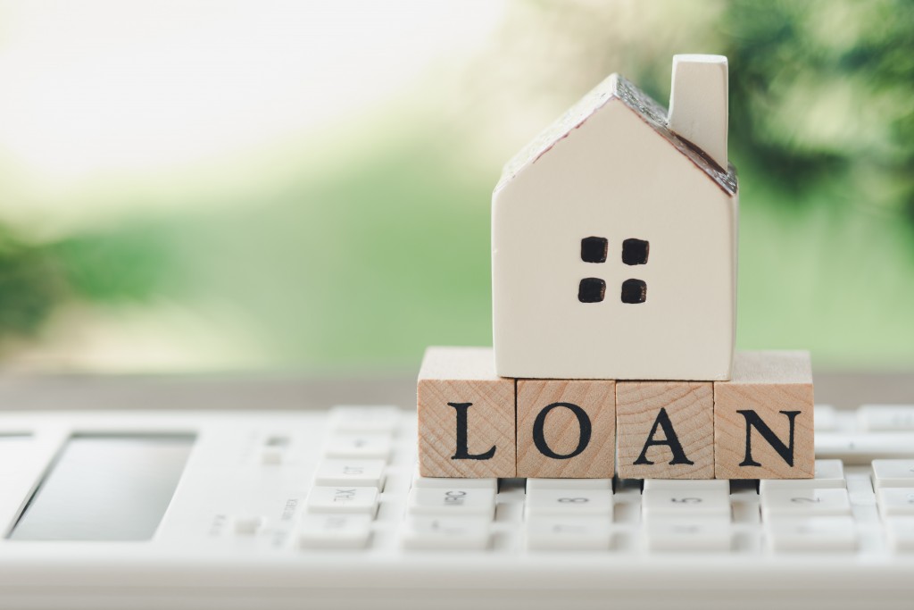 A model house model is placed on wood word LOAN . as background