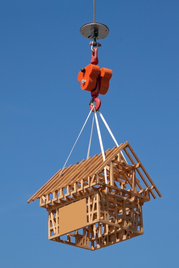 Wooden model house on a hook against blue sky