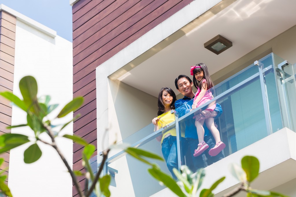 Asian family with child standing on home balcony