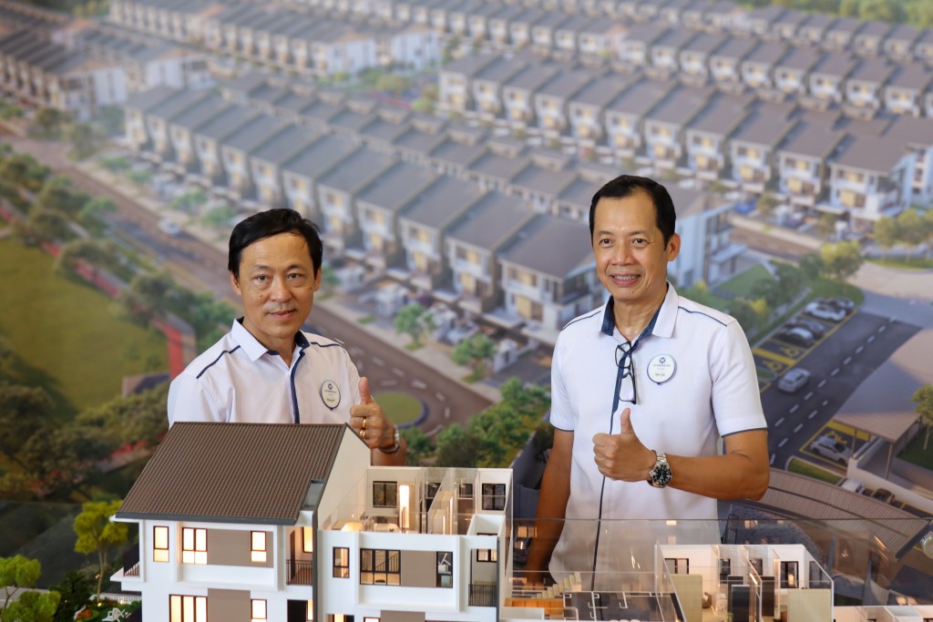 Wong (left) and Teh taking a photo with the scale model of one of the units.